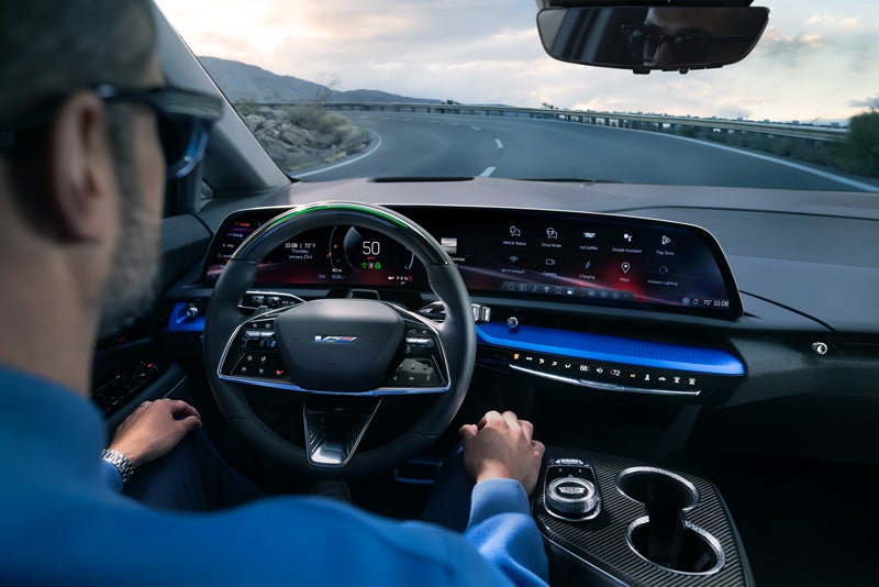 Front View of the 2026 OPTIQ-V Driving Through the Dusk Utilizing its Headlights | Rochester Cadillac in Rochester MN