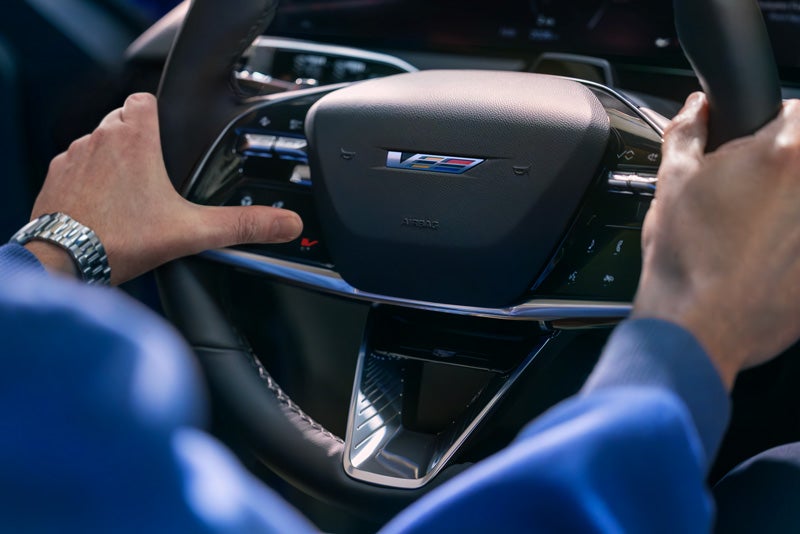 Close-up of a Man About to Press the V-Button on the 2026 OPTIQ-V Steering Wheel | Rochester Cadillac in Rochester MN