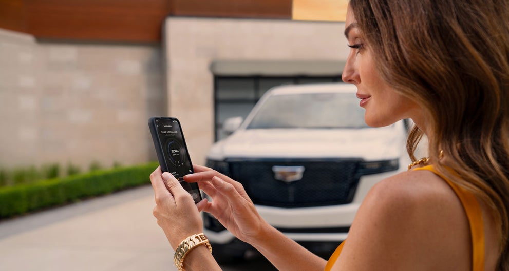 lady checking her mobile with a Cadillac vehicle background | Rochester Cadillac in Rochester MN