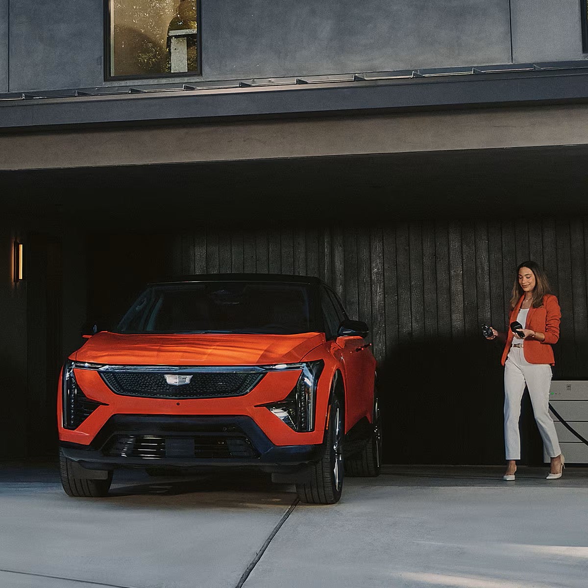 Cadillac OPTIQ plugged into a home charger in a garage
