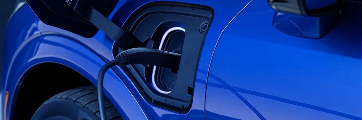 Charging cable plugged into the NACS port of a blue 2027 Cadillac OPTIQ-V